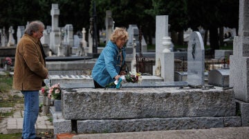 Una mujer deposita un ramo de flores en una lápida del cementerio de la Almudena, a 1 de noviembre de 2023, en Madrid (España).