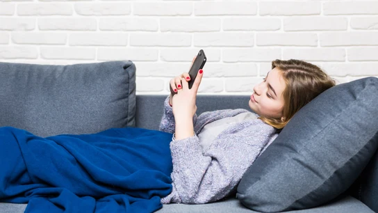 Una chica con su móvil en el sofá. Una chica con su móvil en el sofá.