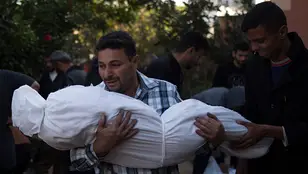 Un palestino coge en brazos a un familiar envuelto que murió tras los ataques israelíes 