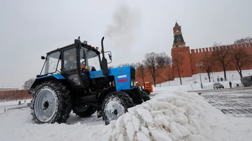 A worker operates a tractor to remove snow from a Moscow square after snowfall.