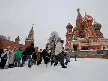 La gente camina a través de un banco de nieve cerca de la muralla del Kremlin y la Catedral de San Basilio después de una fuerte nevada en Moscú
