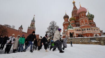 La gente camina a través de un banco de nieve cerca de la muralla del Kremlin y la Catedral de San Basilio después de una fuerte nevada en Moscú
