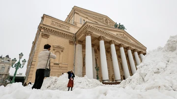 Turistas se sacan fotografías con ventisqueros frente al Teatro Bolshoi después de una fuerte nevada en Moscú.