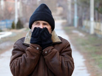 Hombre mayor paseando por la calle con frío