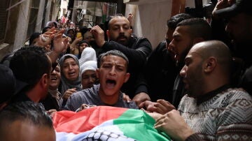 Ciudadanos sacan el cuerpo de un fallecido por los bombardeos con una bandera de Palestina