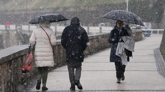 Varias personas pasean por el paseo marítimo de la playa de Ondarreta mientras nieva. Varias personas pasean por el paseo marítimo de la playa de Ondarreta mientras nieva.