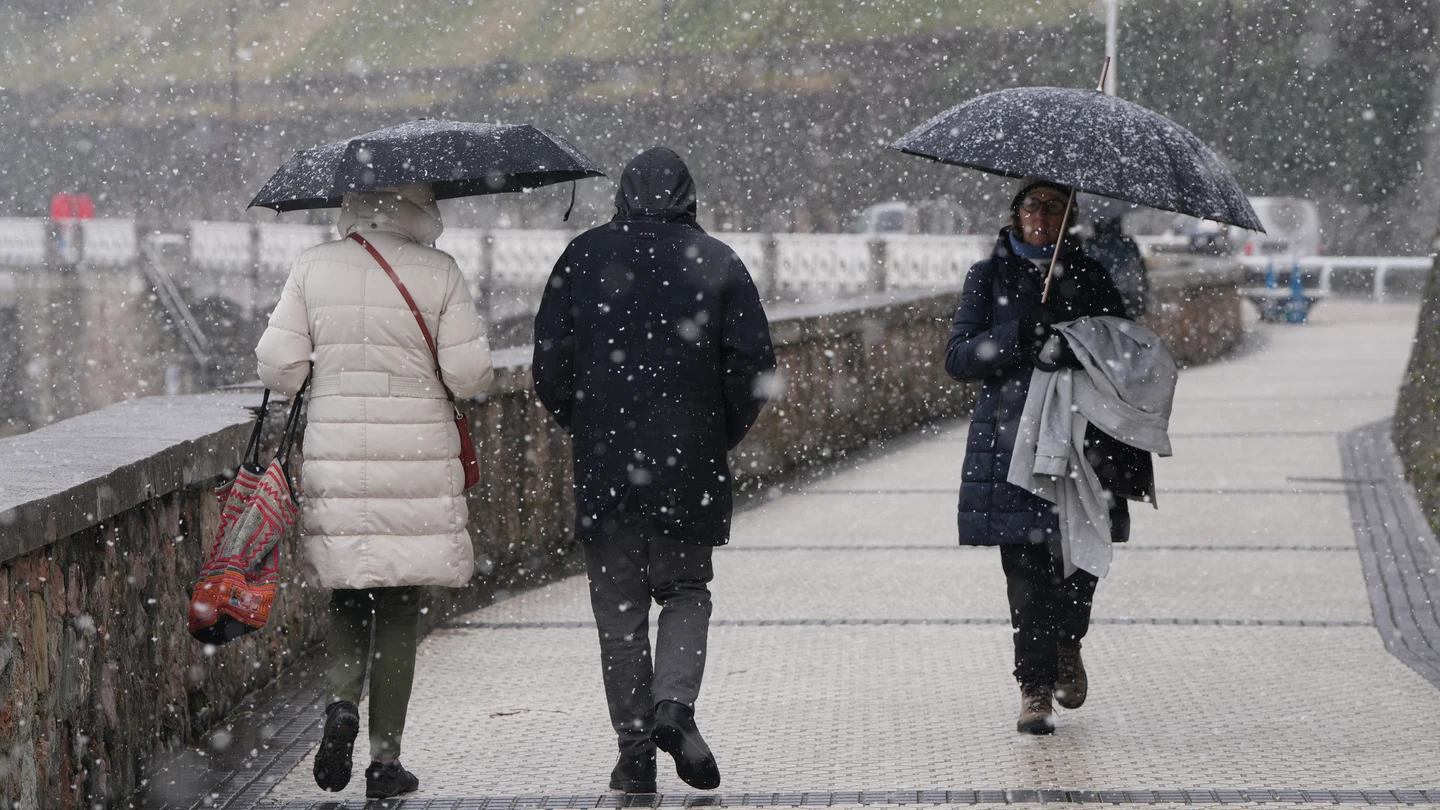 Varias personas pasean por el paseo marítimo de la playa de Ondarreta mientras nieva. Varias personas pasean por el paseo marítimo de la playa de Ondarreta mientras nieva.