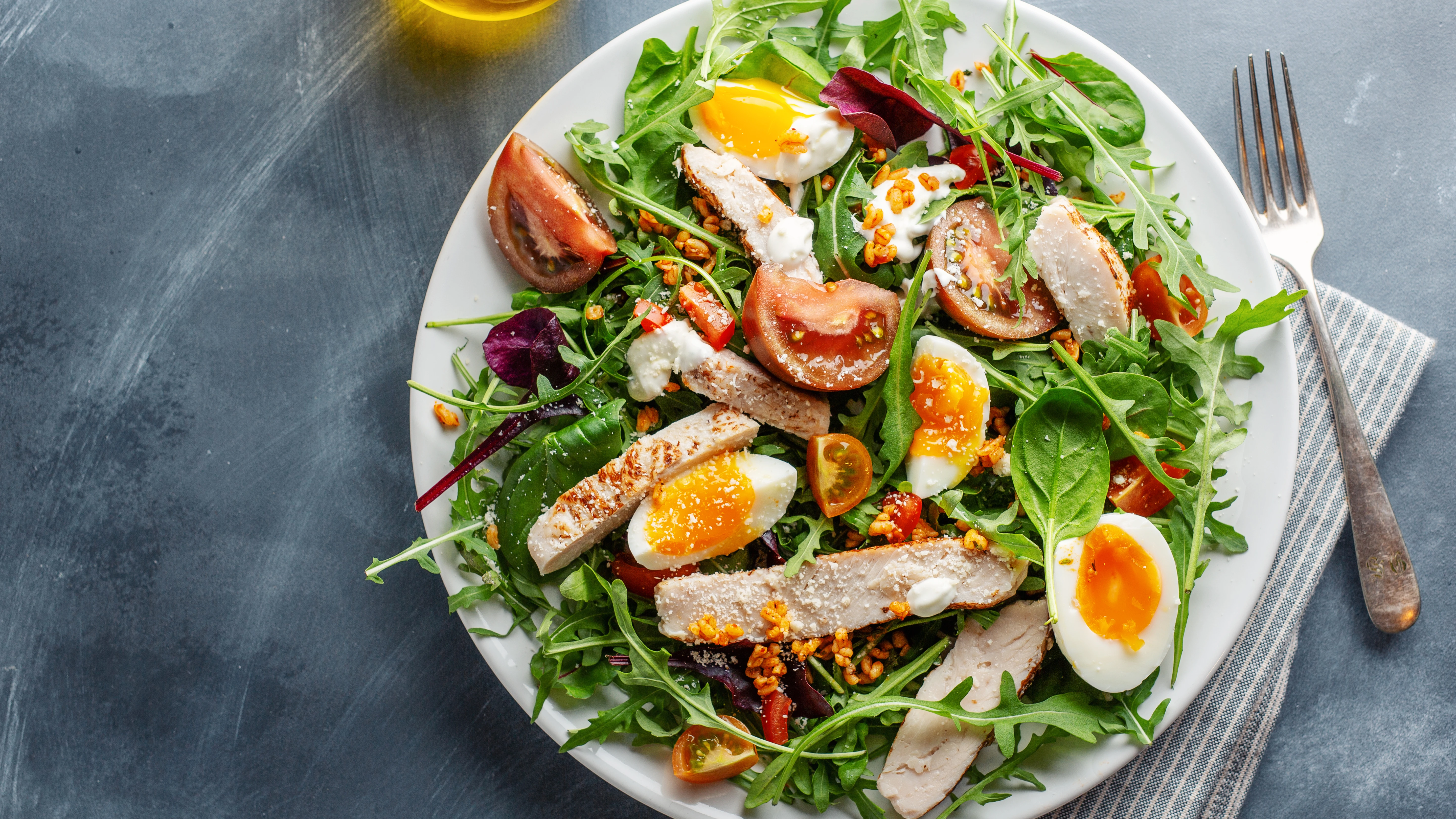 Una ensalada con atún, huevos y tomate. 