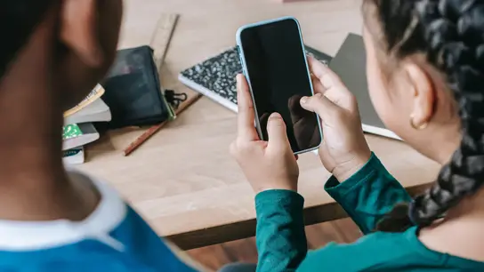 Dos niños en clase con un teléfono móvil. Dos niños en clase con un teléfono móvil.