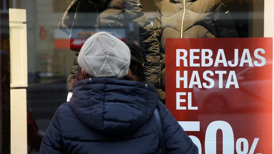 Una persona observa el escaparate de una tienda con rebajas Una persona observa el escaparate de una tienda con rebajas