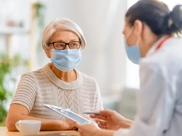 Mujer mayor con mascarilla junto a una doctora Mujer mayor con mascarilla junto a una doctora
