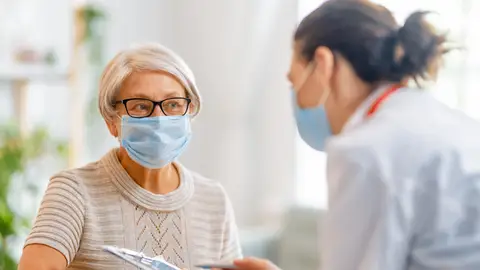 Mujer mayor con mascarilla junto a una doctora Mujer mayor con mascarilla junto a una doctora