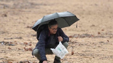 Un hombre recoge pellets bajo la lluvia