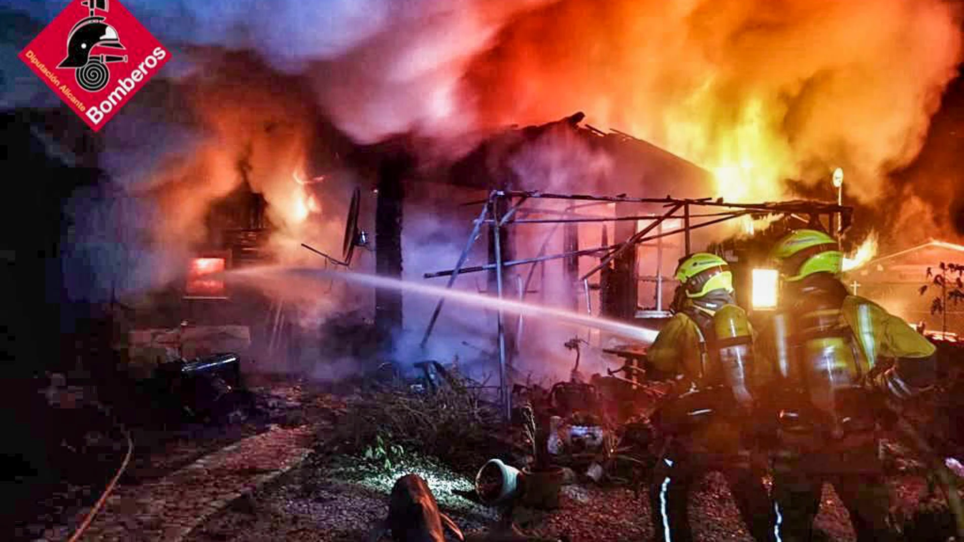 Bomberos intentan apagar el fuego en una casa incendiada en un camping de Benidoleig (Alicante)
