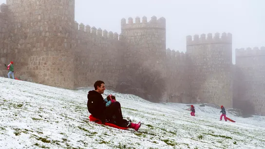 Un hombre se desliza en trineo junto a la muralla de Ávila cubierta por la nieve y el hielo  Un hombre se desliza en trineo junto a la muralla de Ávila cubierta por la nieve y el hielo
