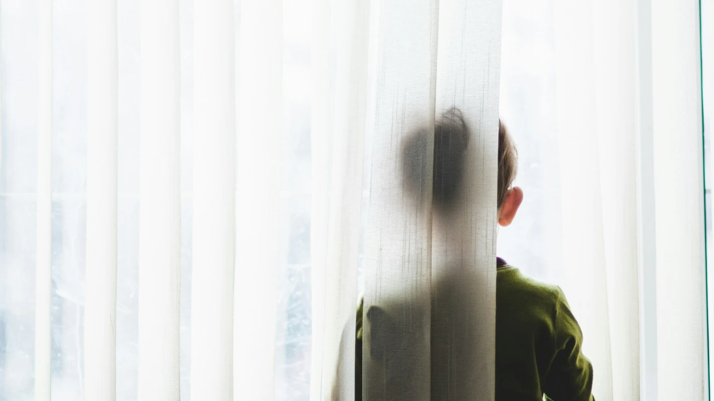 Fotografía de un niño asomado a una ventana. Fotografía de un niño asomado a una ventana.