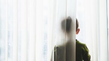 Fotografía de un niño asomado a una ventana.