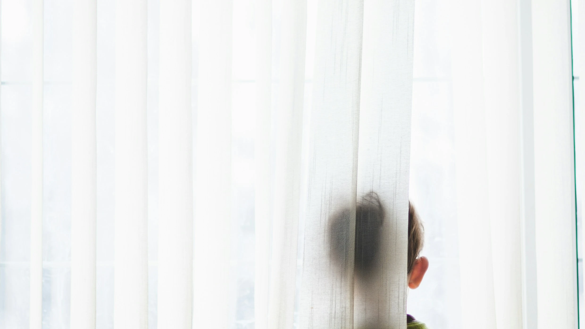 Fotografía de un niño asomado a una ventana.