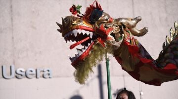 Una mujer sujeta la cabeza de un dragón durante las celebraciones del Año Nuevo Chino en la plaza de Distrito de Usera, a 20 de enero de 2023, en Madrid (España)