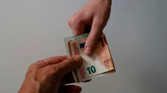 Dos personas sujetan un billete de 10 euros Dos personas sujetan un billete de 10 euros