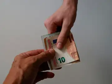 Dos personas sujetan un billete de 10 euros