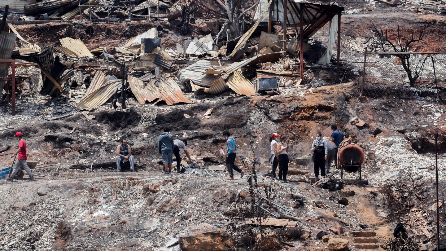 Los vecinos limpian los escombros de las casas quemadas tras los incendios forestales en Viña del Mar, Chile. Los vecinos limpian los escombros de las casas quemadas tras los incendios forestales en Viña del Mar, Chile.