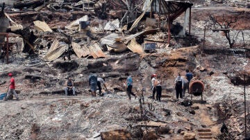 Los vecinos limpian los escombros de las casas quemadas tras los incendios forestales en Viña del Mar, Chile.