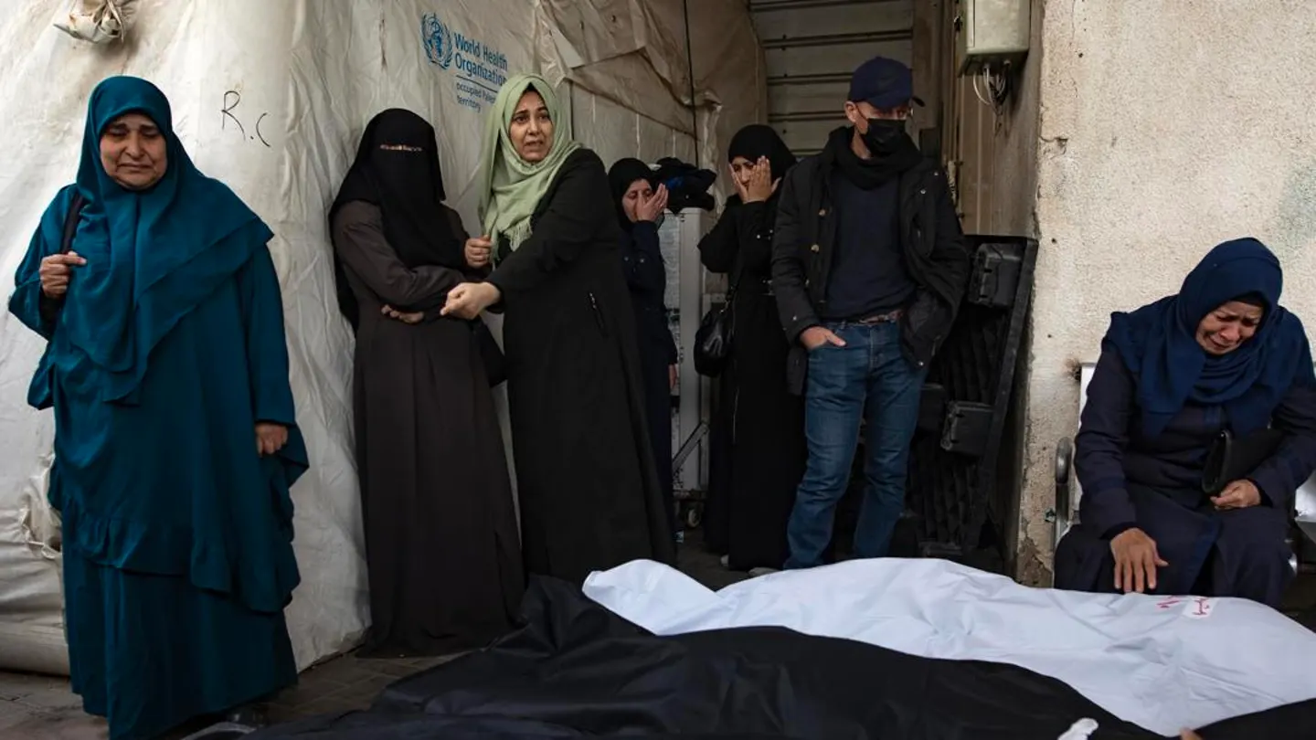 Los palestinos de la familia Ghannam se sientan junto a los cuerpos envueltos de algunos de sus familiares Los palestinos de la familia Ghannam se sientan junto a los cuerpos envueltos de algunos de sus familiares