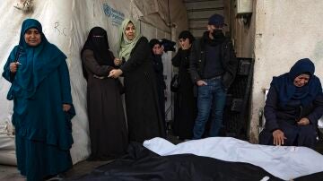 Los palestinos de la familia Ghannam se sientan junto a los cuerpos envueltos de algunos de sus familiares