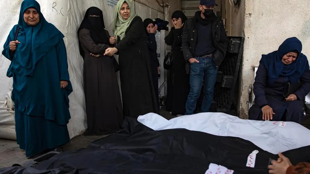 Los palestinos de la familia Ghannam se sientan junto a los cuerpos envueltos de algunos de sus familiares