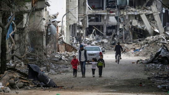 Una familia palestina camina entre la destrucci&oacute;n en el campo de refugiados de Al Bureije (Gaza) 