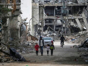 Una familia palestina camina entre la destrucci&oacute;n en el campo de refugiados de Al Bureije (Gaza) 