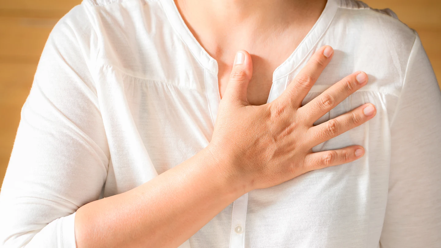Una mujer con la mano en el pecho. El dolor en el pecho es el síntoma más común del infarto en hombres y en mujeres Una mujer con la mano en el pecho. El dolor en el pecho es el síntoma más común del infarto en hombres y en mujeres