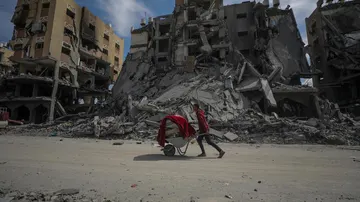 Un palestino empuja una carretilla entre los escombros de casas destruidas en Gaza, a 14 de marzo de 2024. 