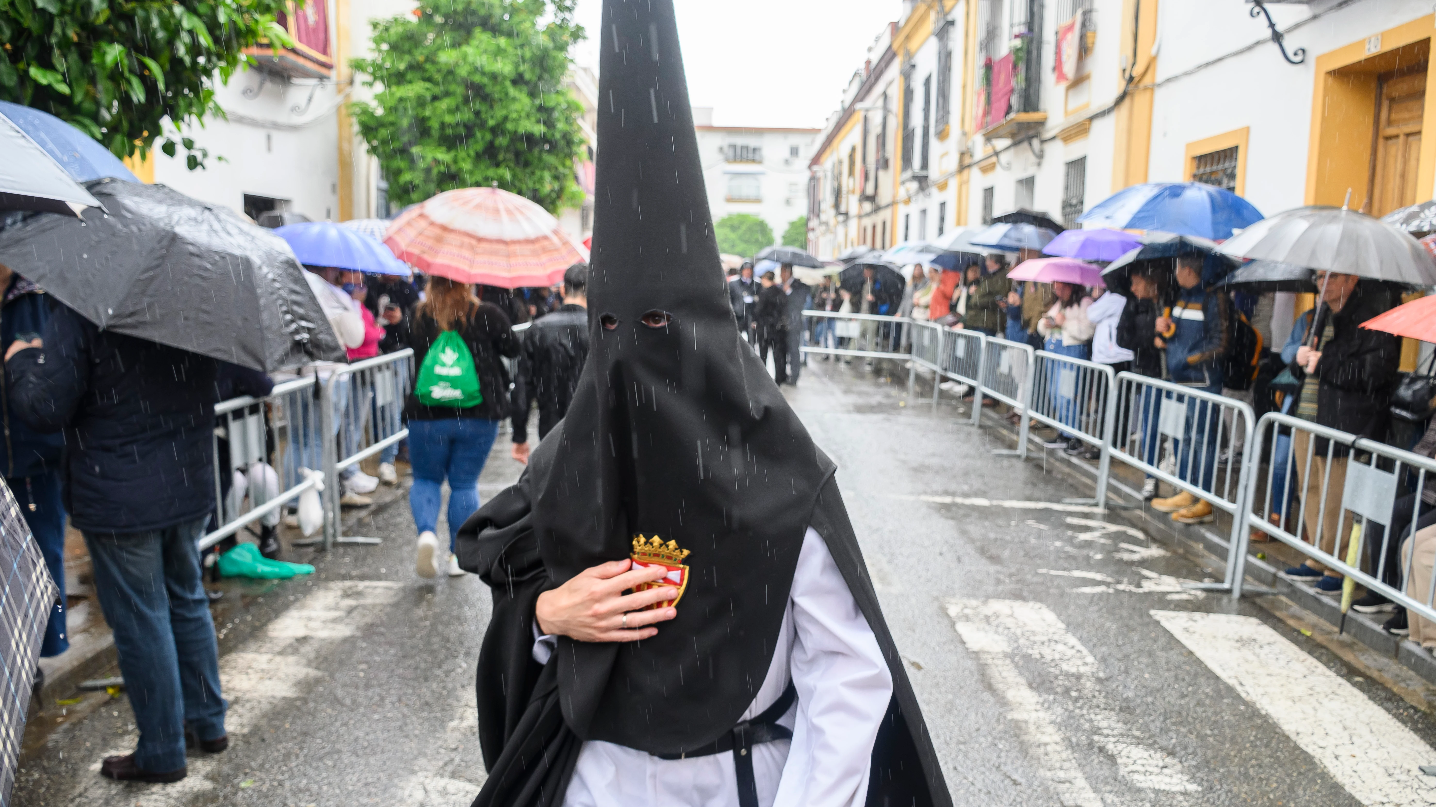 Un nazareno de la hermandad de Santa Genoveva, una de las nueve cofradías que salen en procesión el Lunes Santo en Sevilla, se dirige a su templo este lunes en el que no procesionará tras la decisión tomada debido a la lluvia que desde primera hora de la mañana cae en la capital andaluza.