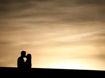 Pareja dándose un beso al atardecer Pareja dándose un beso al atardecer