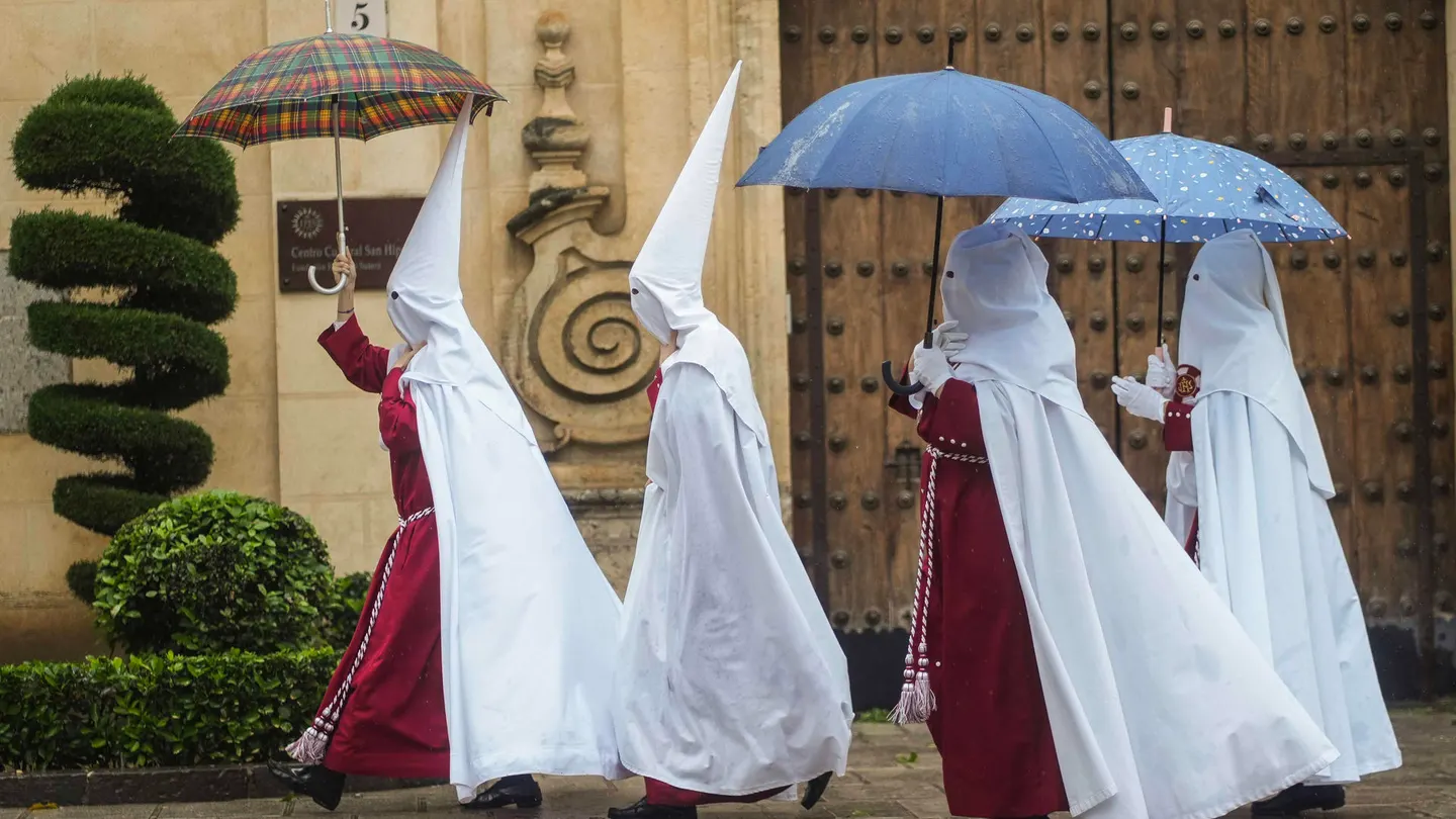 Nazarenos se protegen de la lluvia con paraguas en Córdoba. Nazarenos se protegen de la lluvia con paraguas en Córdoba.