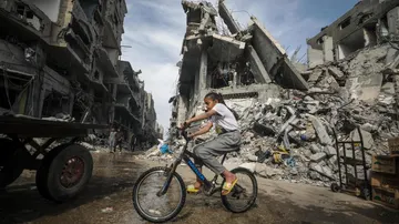 Una niña palestina monta en bicicleta rodeada de edificios destruidos por los ataques de Israel en el campamento de refugiados de Nuseirat, Gaza