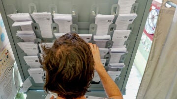 Una persona dentro de una cabina electoral para coger su papeleta para votar.