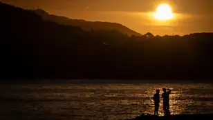 Dos personas observan el amanecer este jueves en la playa de Ondarreta de San Sebastián. 