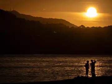 Dos personas observan el amanecer este jueves en la playa de Ondarreta de San Sebastián. 