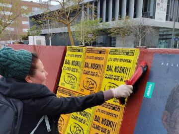 Una integrante del partido Ongi Etorri pegando carteles en la campa&ntilde;a electoral de las elecciones vascas de 2024