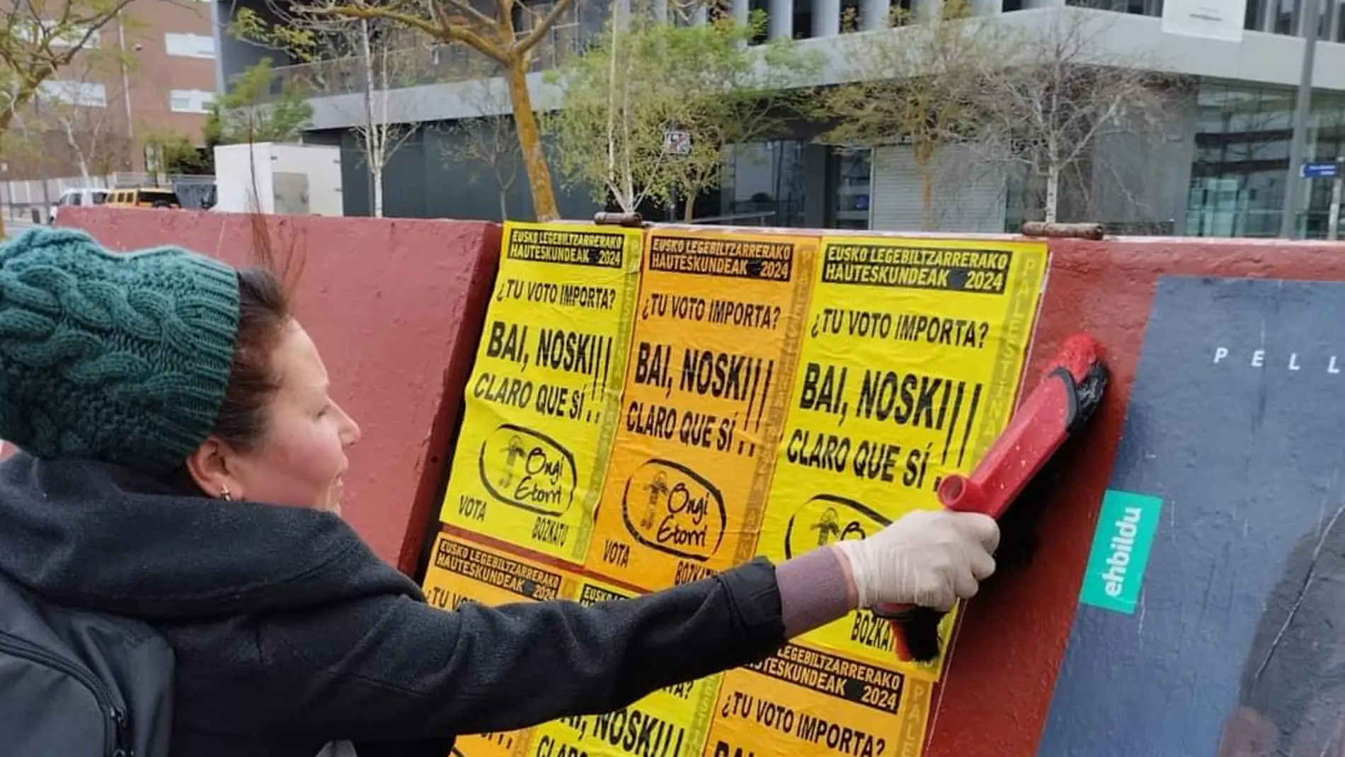 Una integrante del partido Ongi Etorri pegando carteles en la campaña electoral de las elecciones vascas de 2024