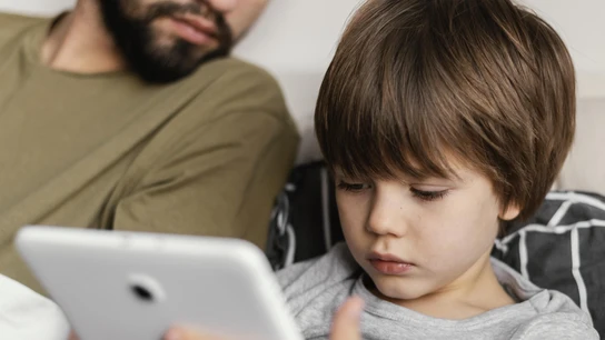 Un padre con su hijo mirando cosas en un móvil o tableta. Un padre con su hijo mirando cosas en un móvil o tableta.