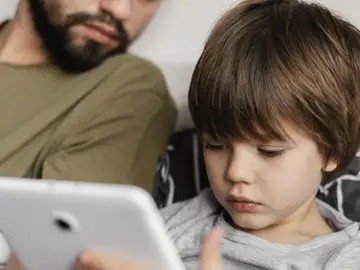 Un padre con su hijo mirando cosas en un móvil o tableta.