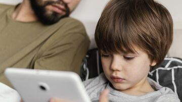Un padre con su hijo mirando cosas en un móvil o tableta.