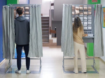 Dos personas ejercen su derecho a voto en una cabina en un colegio electoral, a 28 de mayo de 2023.