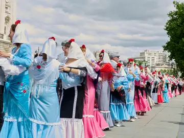 Una fila de chulapas bailando por Madrid en las fiestas de San Isidro