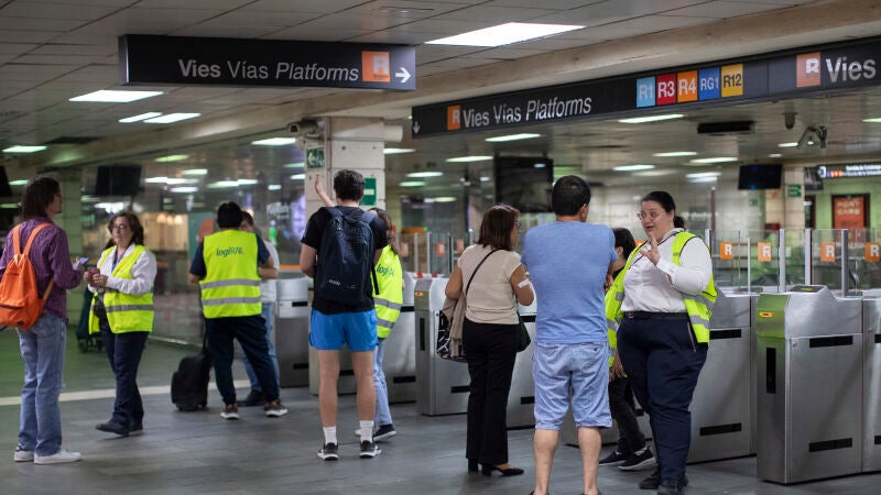 Una informadora da indicaciones a varios usuarios en la estación de cercanías de Renfe de Plaça Catalunya, este domingo en que ha habido se ha suspendido el servicio debido a las incidencias ocurridas en Rodalies a raíz de un nuevo robo de cobre