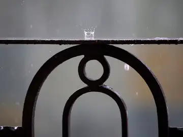 Detalle de la lluvia cayendo sobre la barandilla de un balcón.